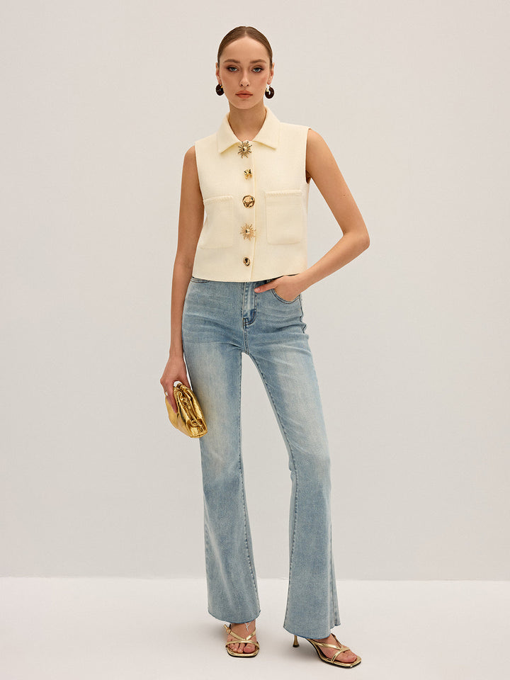 Full length shot of the ivory button vest styled with flared jeans and a gold clutch