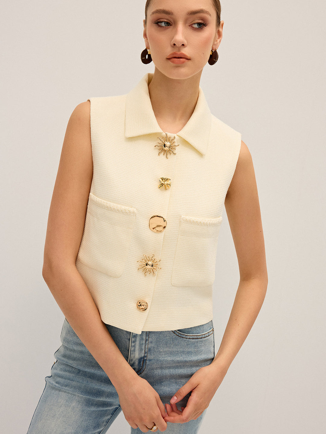 Angled view of the cream collared vest showing the boxy cropped fit over denim