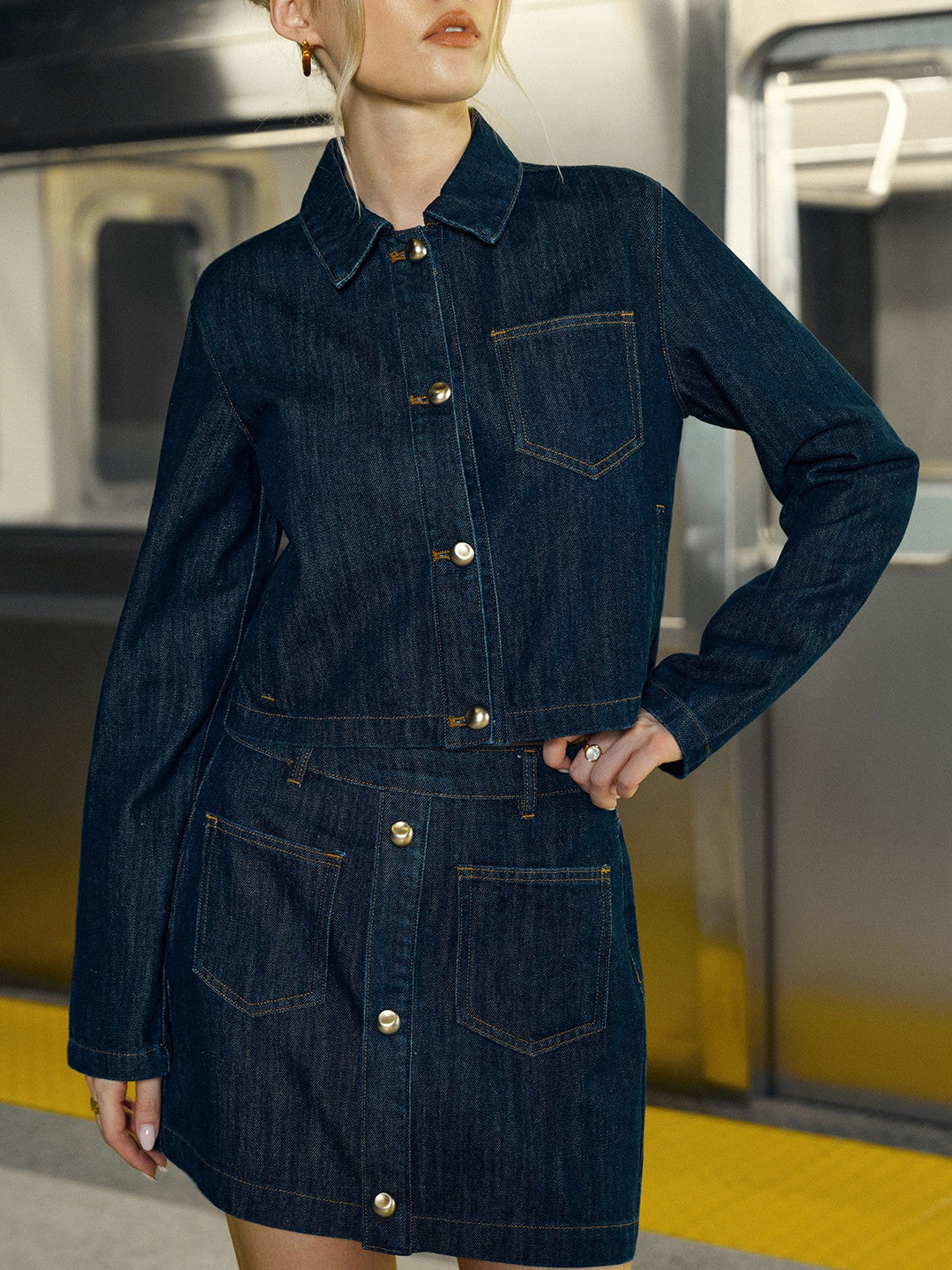 Front detail of raw indigo crop denim jacket with gold buttons and chest patch pocket