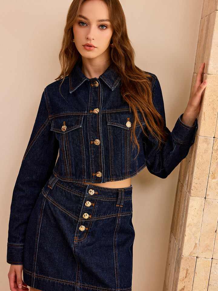 Close front view of the dark wash denim jacket with gold buttons and chest pockets