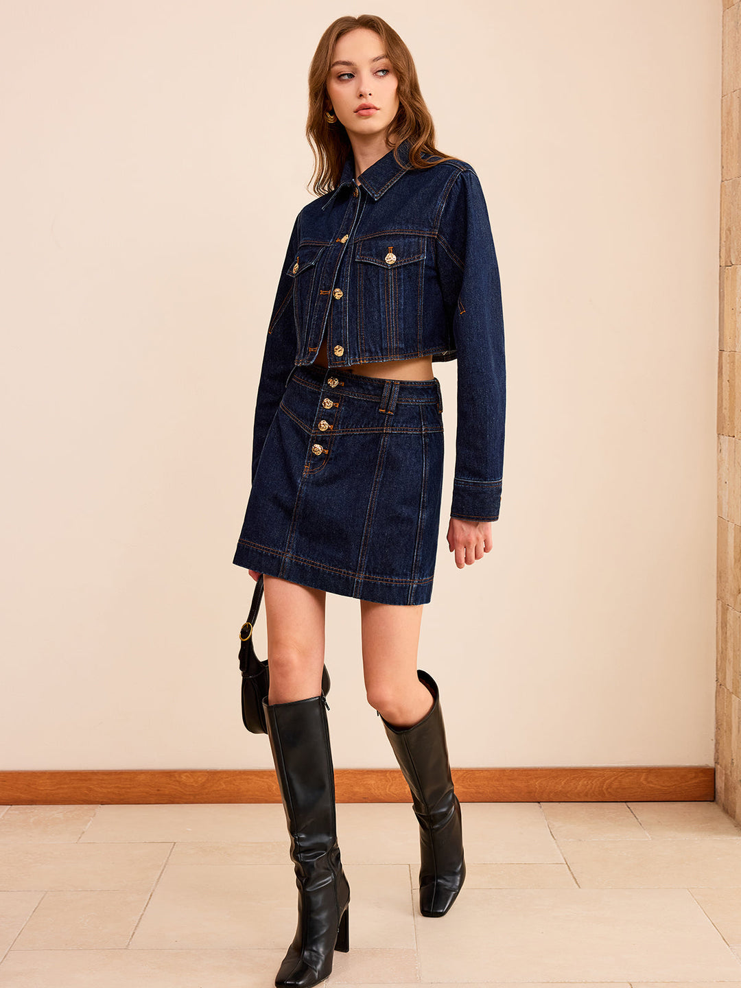 Side view of the short indigo denim jacket showing the raw cropped hem