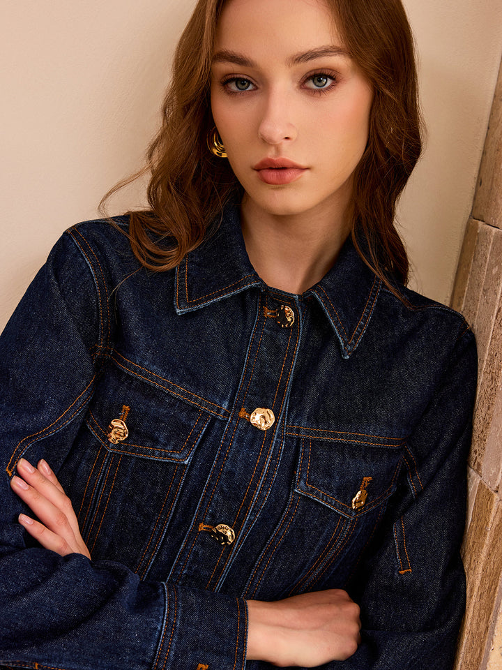 Close-up of the gold metal buttons and topstitched flap pockets on the denim jacket