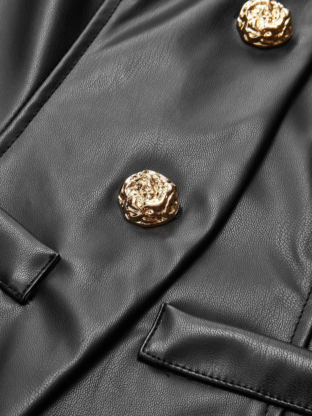Close-up of ornate gold metal buttons on the placket of a black leather look jacket
