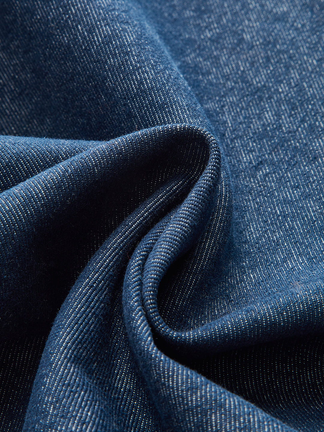 Macro of indigo blue denim twill fabric used for the metal button suede collar jacket