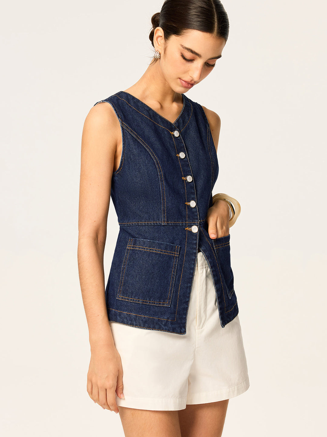 Side angle of dark denim vest showing asymmetric split hem and curved seams