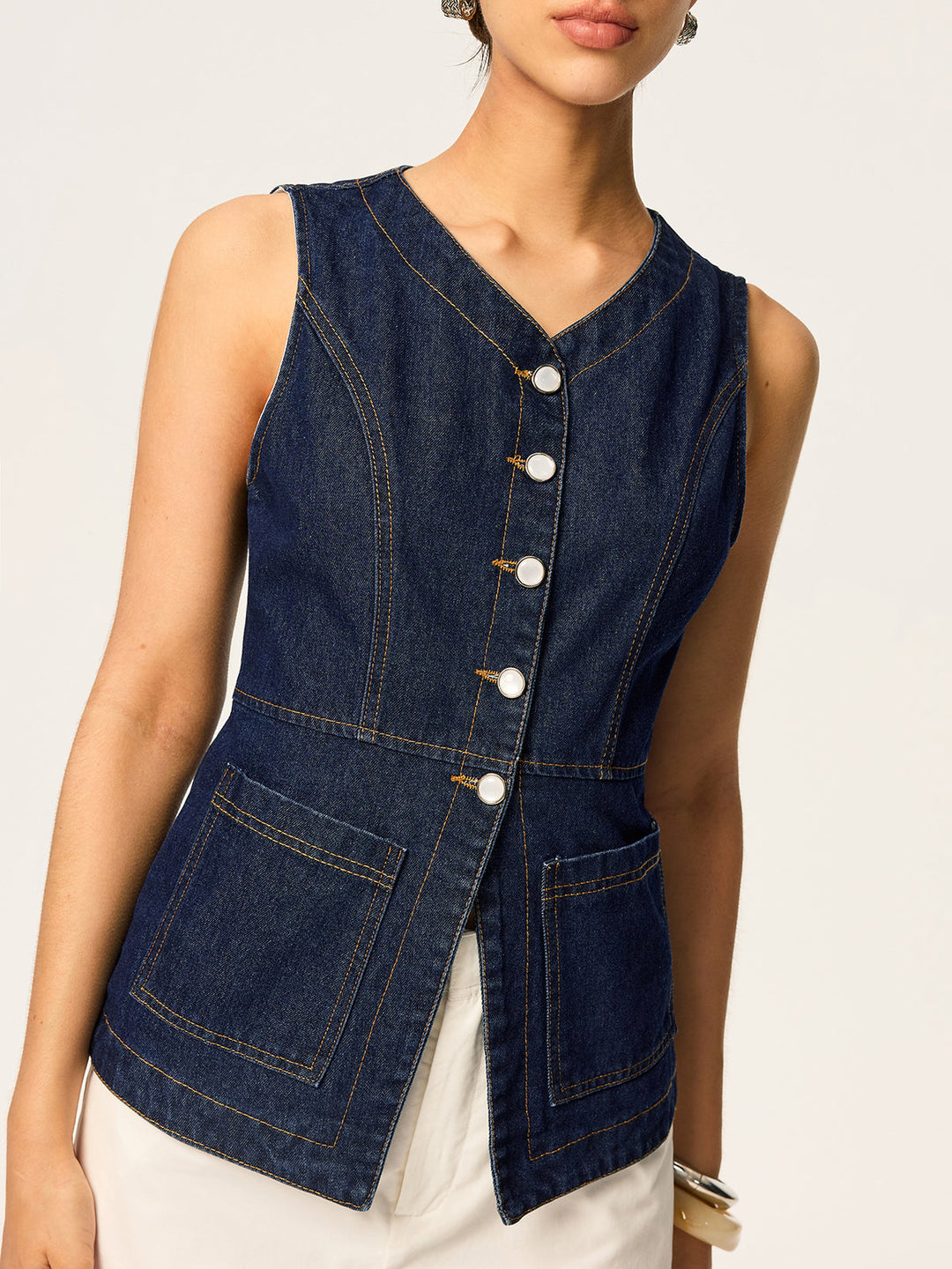 Cropped view of navy denim vest with contrast stitching and large patch pocket