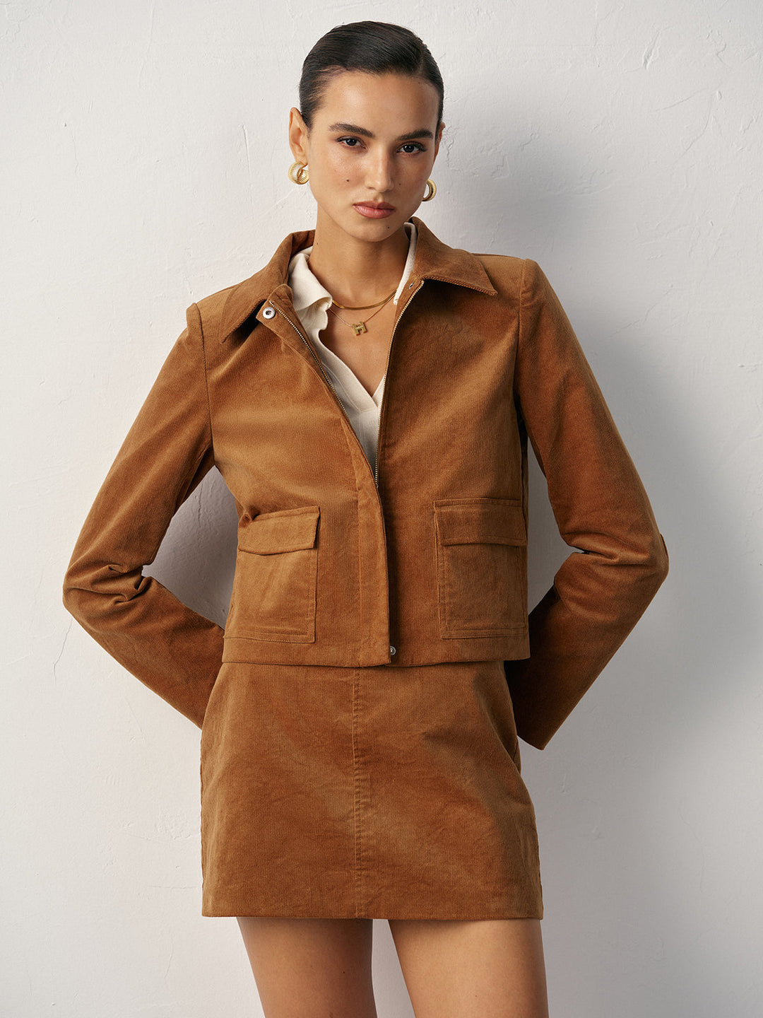 Women's tan corduroy jacket with hands in pockets and matching mini skirt