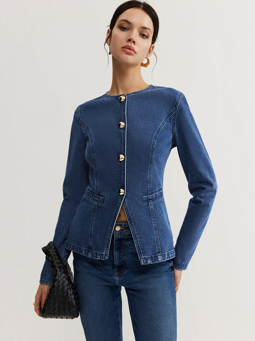 Model in the fitted denim button down jacket holding a black woven bag