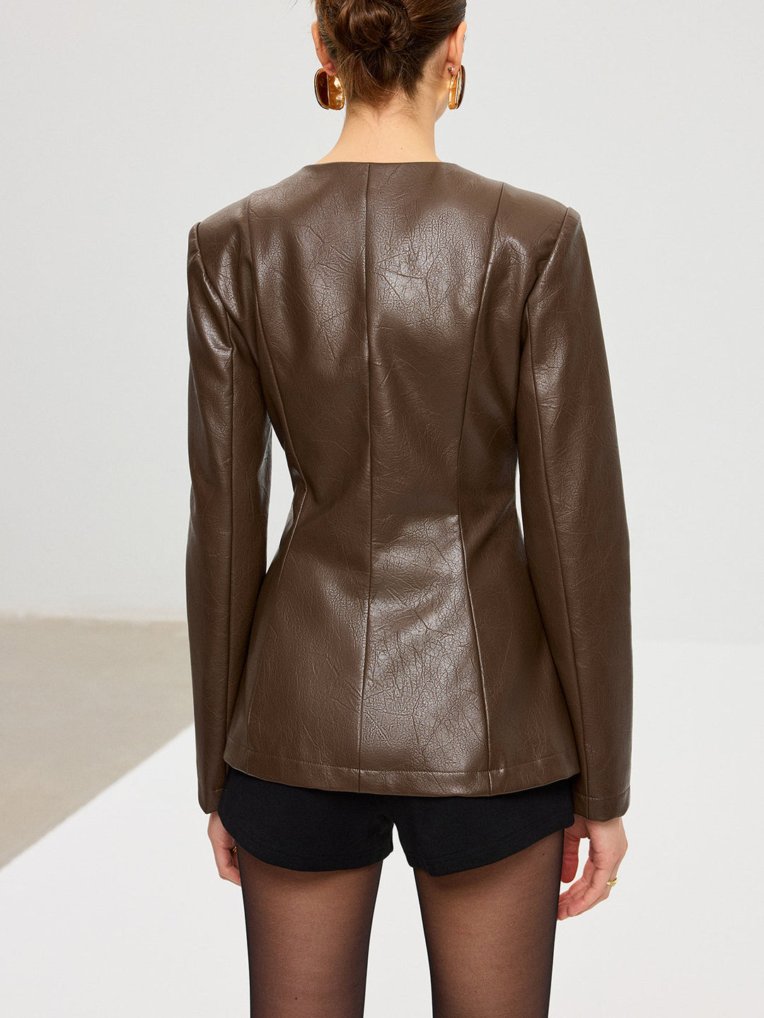 Back view of fitted brown PU leather jacket showing centre seam and shaped waist