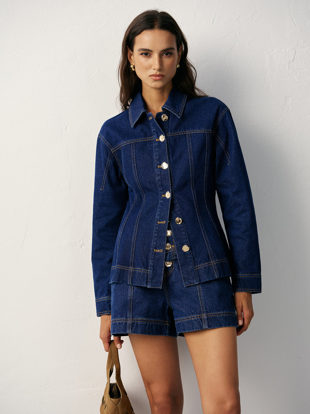 Full-length shot of indigo denim jacket and shorts co-ord with tan shoulder bag