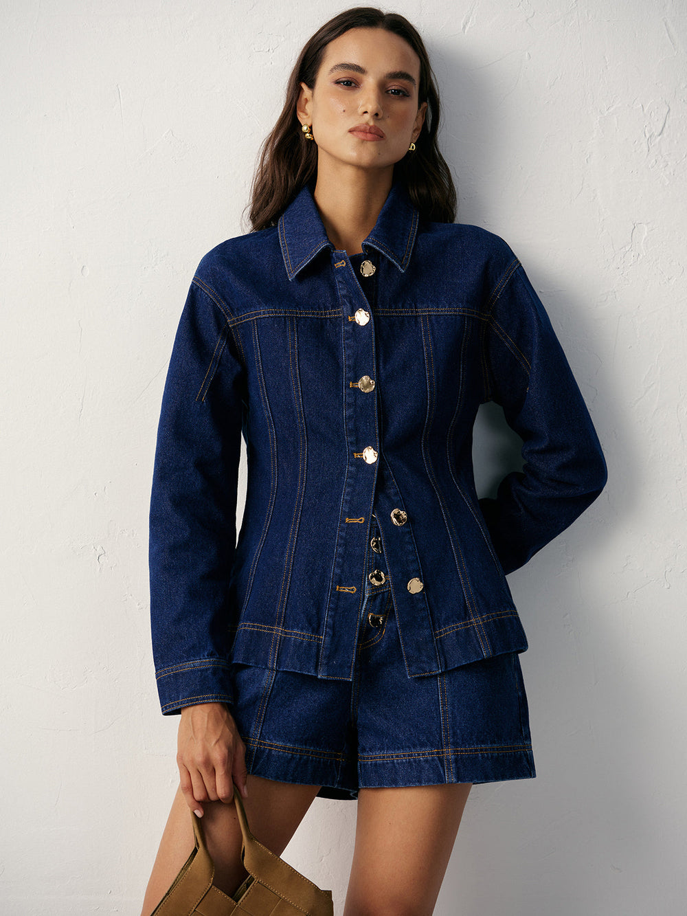 Front view of women's dark blue denim jacket with gold metal buttons and nipped waist