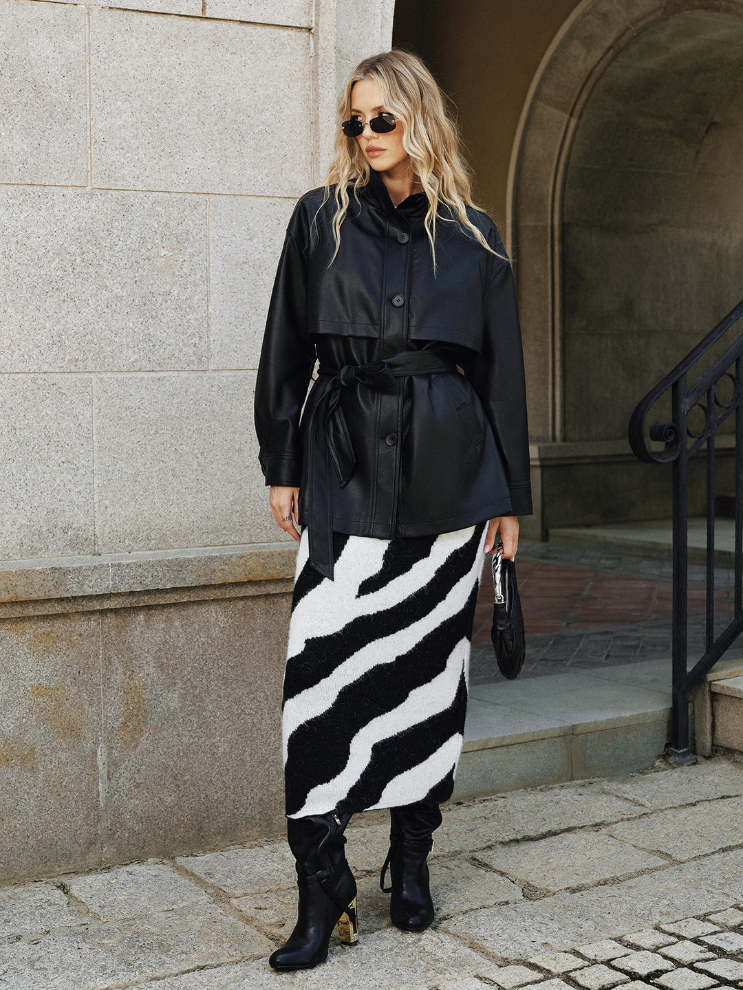 Black belted faux leather jacket styled with a black and white striped midi skirt