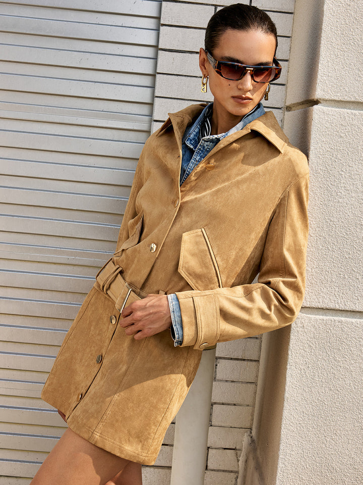 Leaning pose showing the belted waist of the camel suede jacket