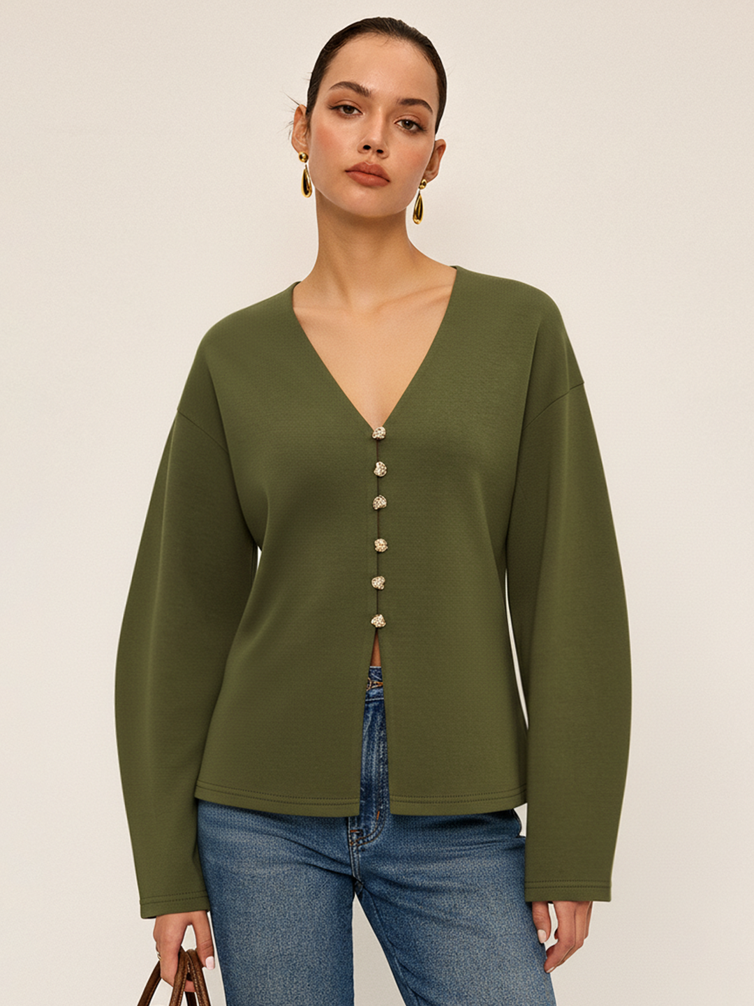 Model wears dark olive green V-neck longline cardigan with gold buttons and blue jeans, front view