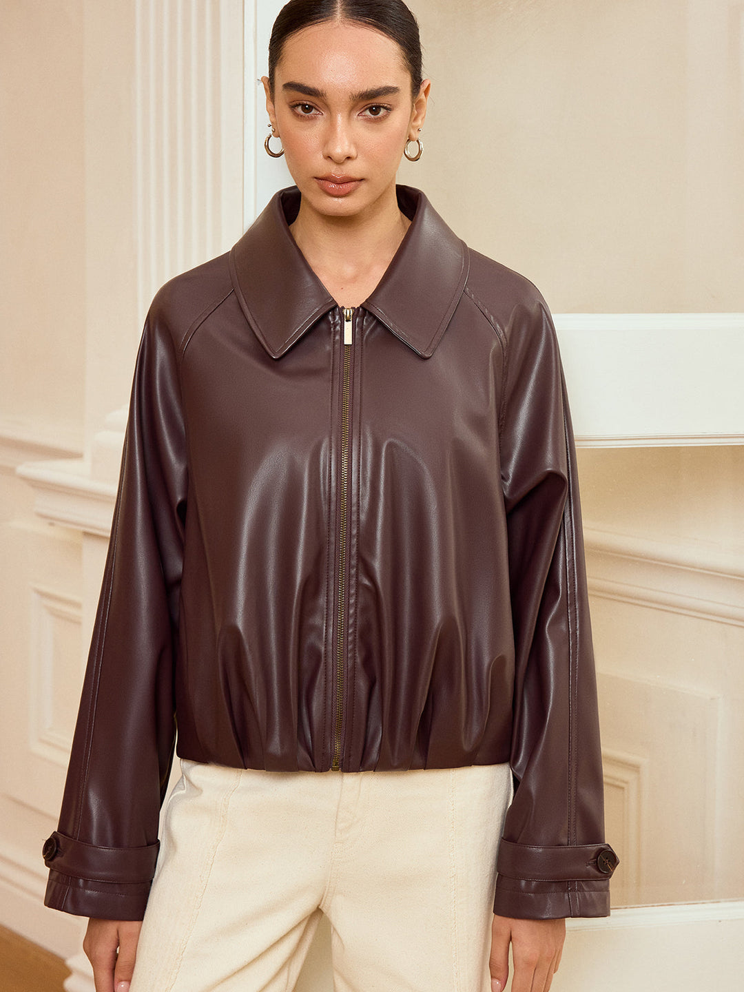 Front view of brown faux leather jacket zipped up with point collar and elasticated hem