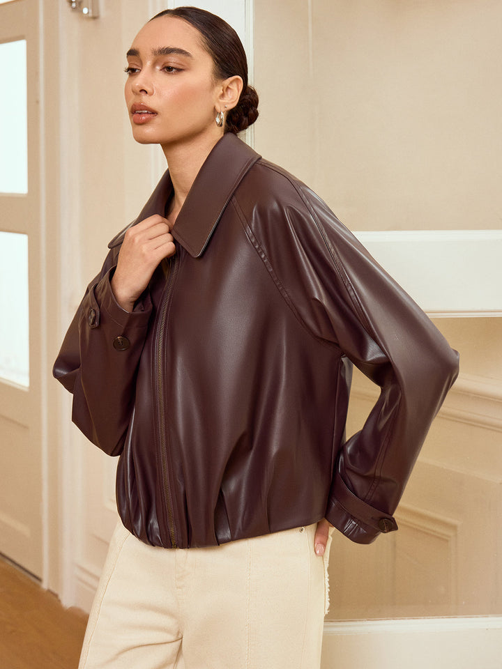 Side view of brown faux leather bomber jacket showing drop shoulder and buttoned cuff