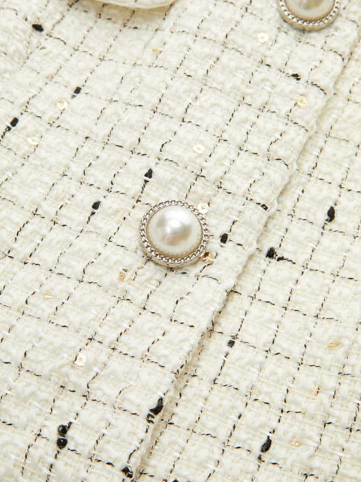 Close-up of the pearl button and sequin flecked ivory tweed weave on the cropped jacket
