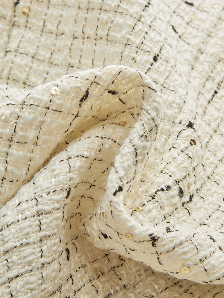 Fabric detail of ivory boucle tweed with black flecks and gold sequin threads
