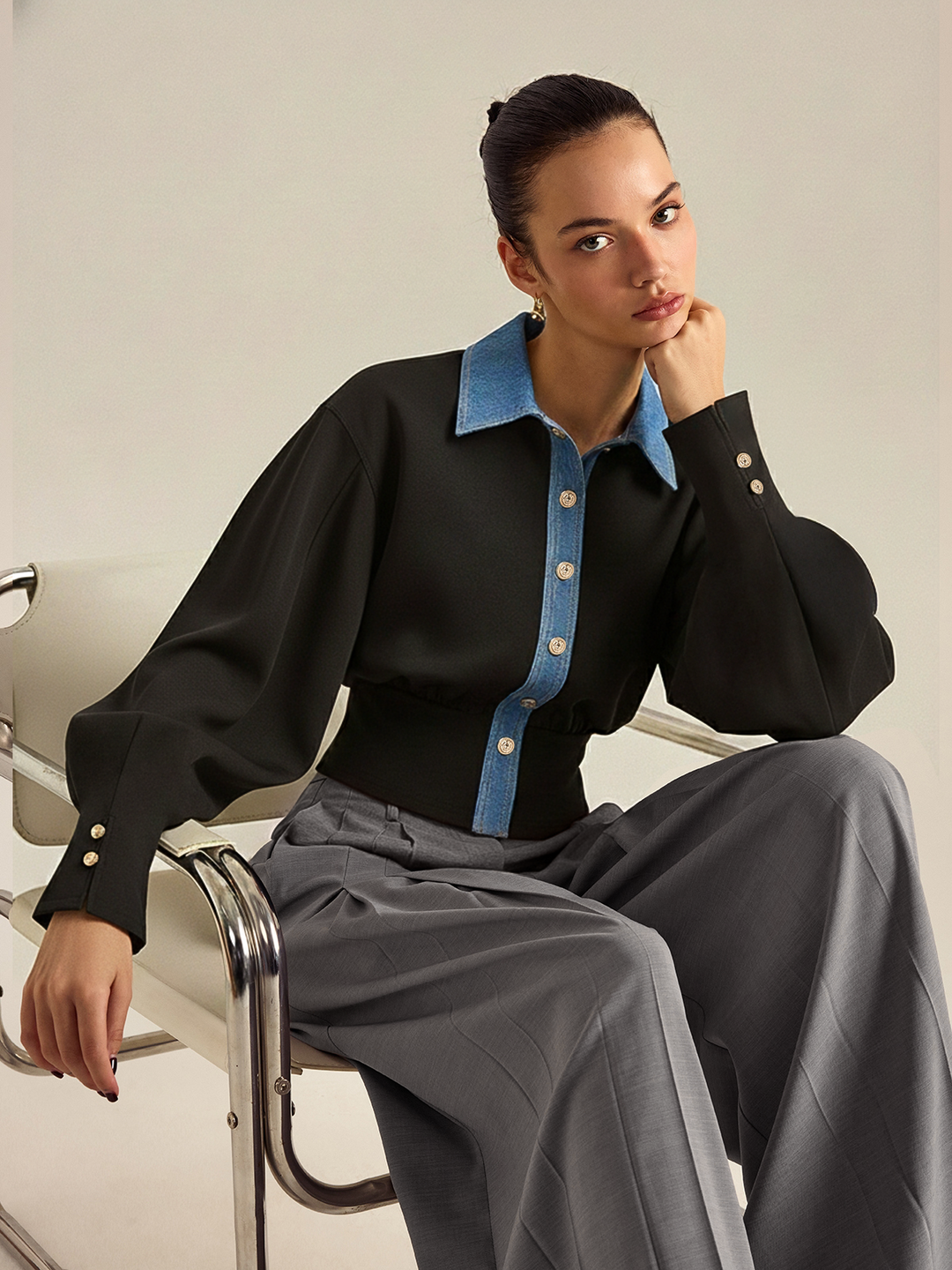 Seated pose in the denim trim buttoned top with balloon sleeves and grey trousers
