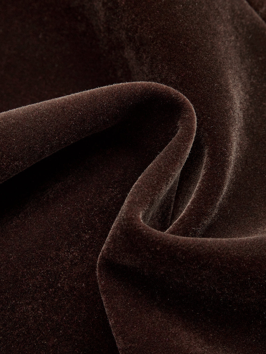 Swirled close-up of the plush dark brown velvet fabric