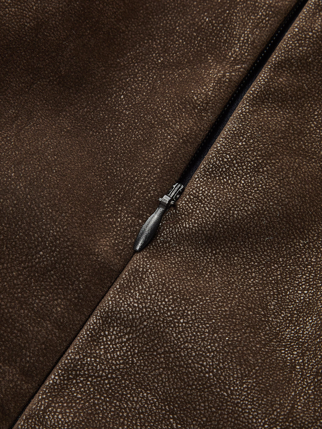 Macro of pebbled distressed faux leather surface and side zip on brown vest