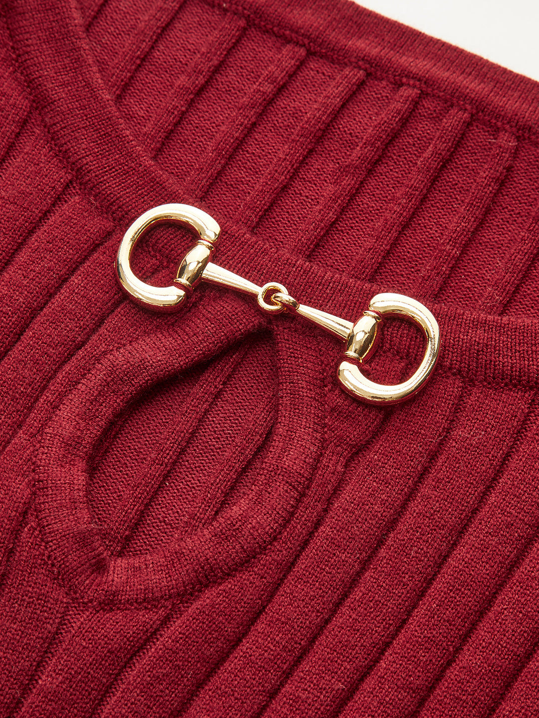 Close-up of the polished gold horsebit hardware at the neckline of the red knit dress