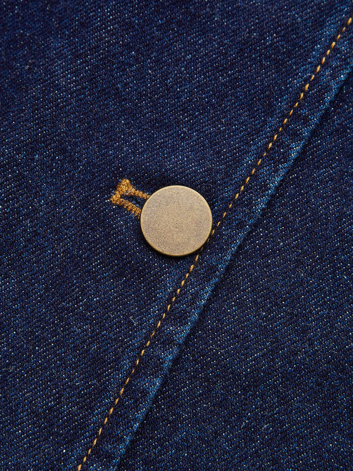 Close-up of antique brass button on the placket of a navy contrast collar denim jacket