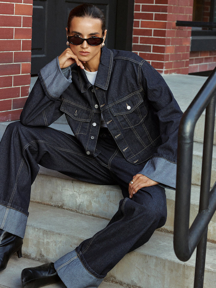 Dark indigo denim jacket with turn-up cuffs, model seated on brownstone steps