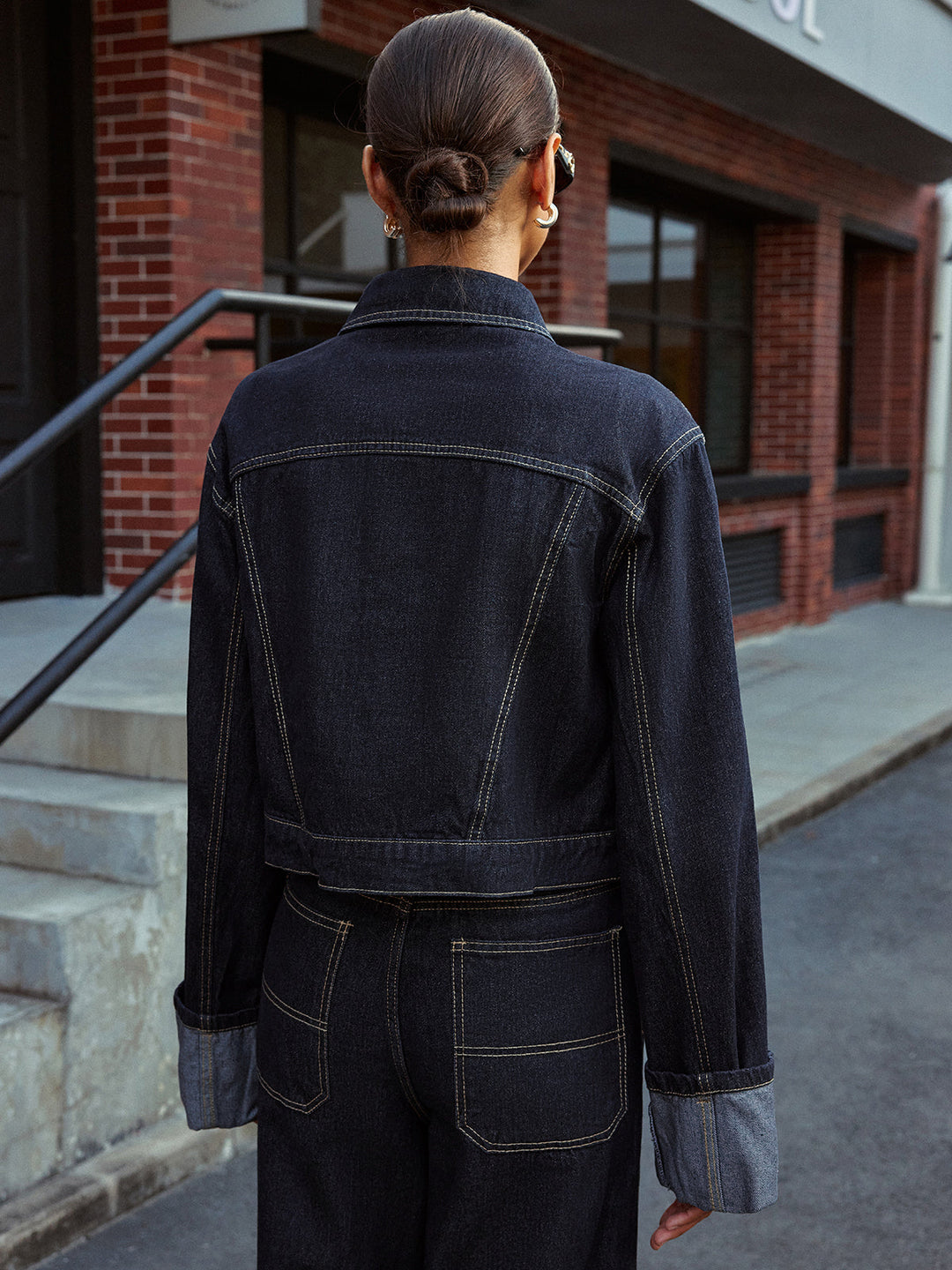 Back view of the dark blue cuffed sleeve denim jacket with yoke seam detail