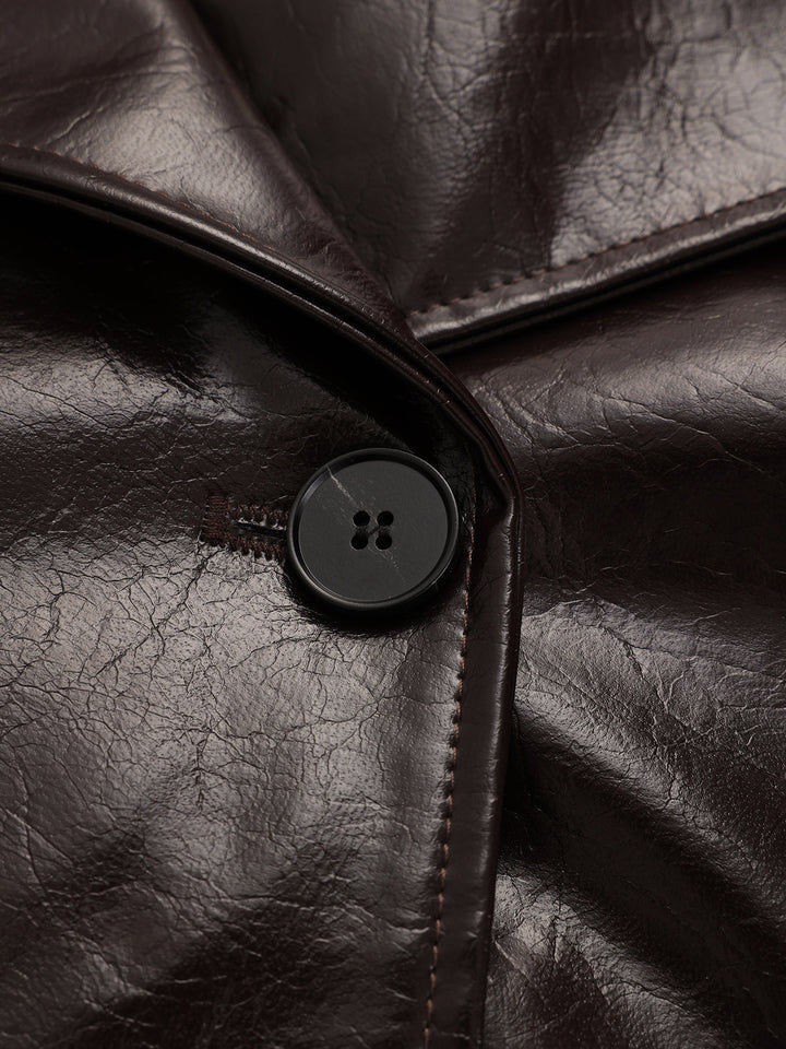 Close-up of the black four-hole button and topstitched lapel on the brown leather coat