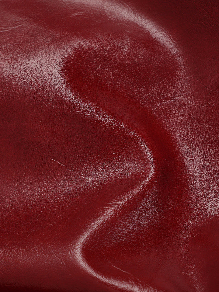 Close-up of glossy wine red faux leather fabric showing soft draping and sheen