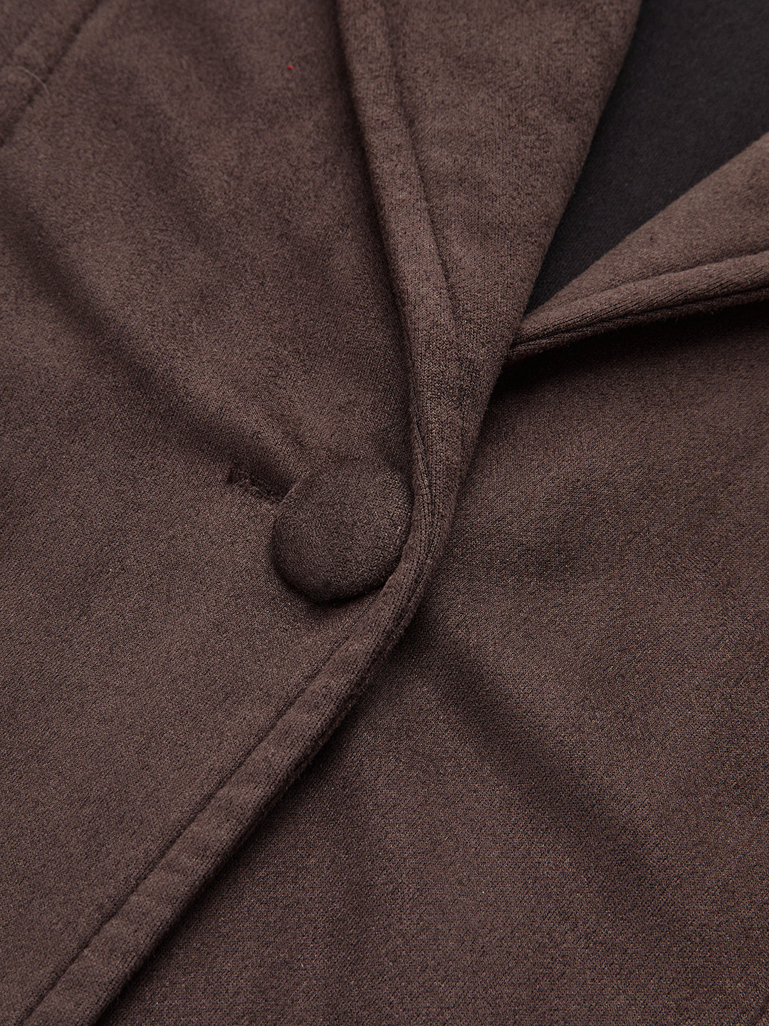 Close-up of the covered button and shawl lapel edge on the belted brown jacket