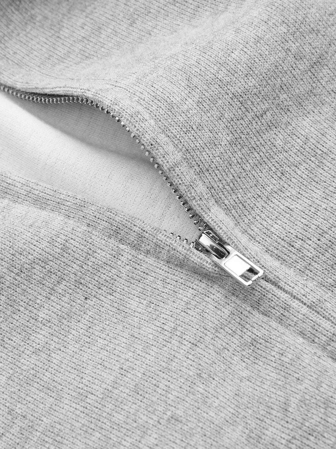 Close-up of the silver zip pull and brushed inner lining of a grey zip-up hoodie