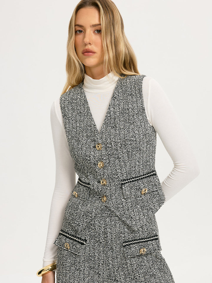 Front view of grey tweed vest with braided black trim on pockets and hem