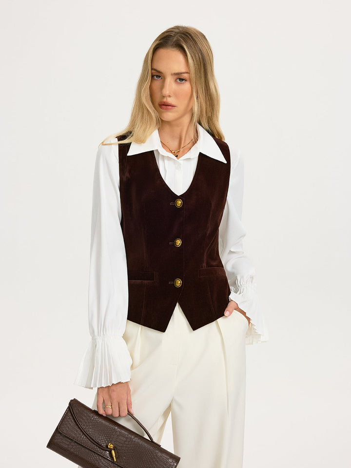 Three-quarter view of the brown velvet waistcoat styled with a pointed-collar white shirt and cream wide-leg trousers