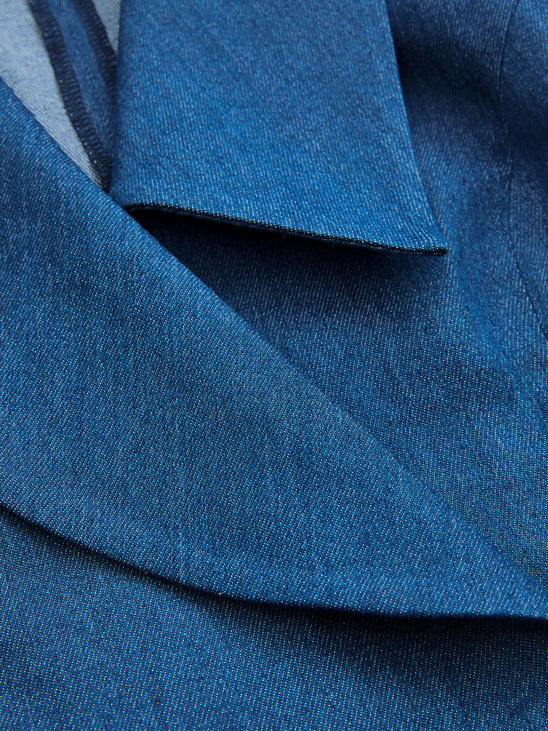 Close-up of the shawl collar and crossover wrap front of the blue denim vest