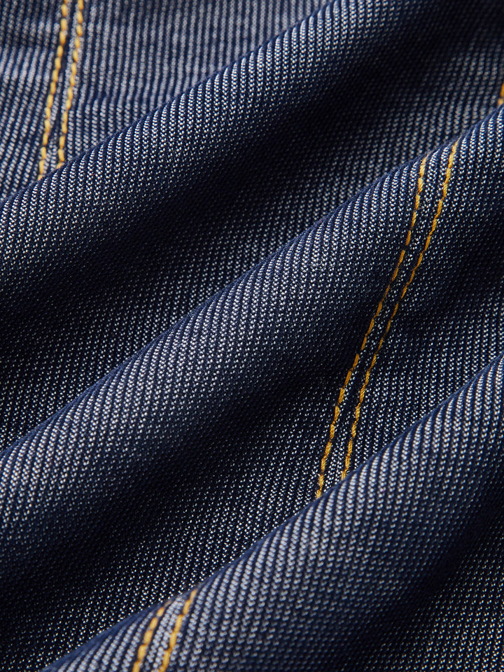 Close-up of dark navy denim fabric with contrast gold topstitching