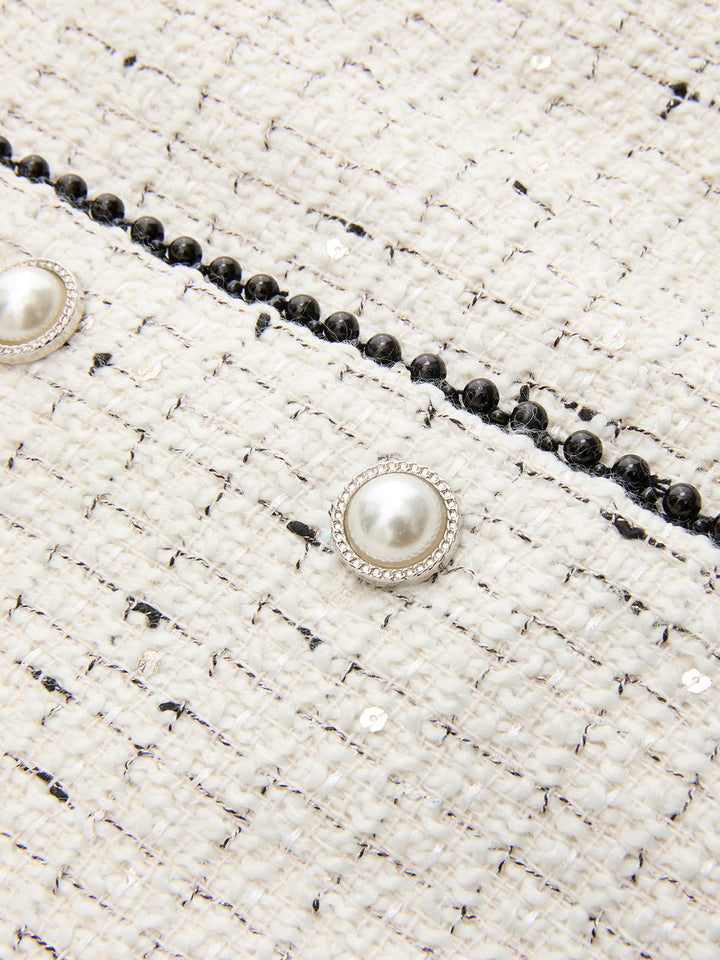 Macro of pearl button and black beaded trim on off-white tweed vest