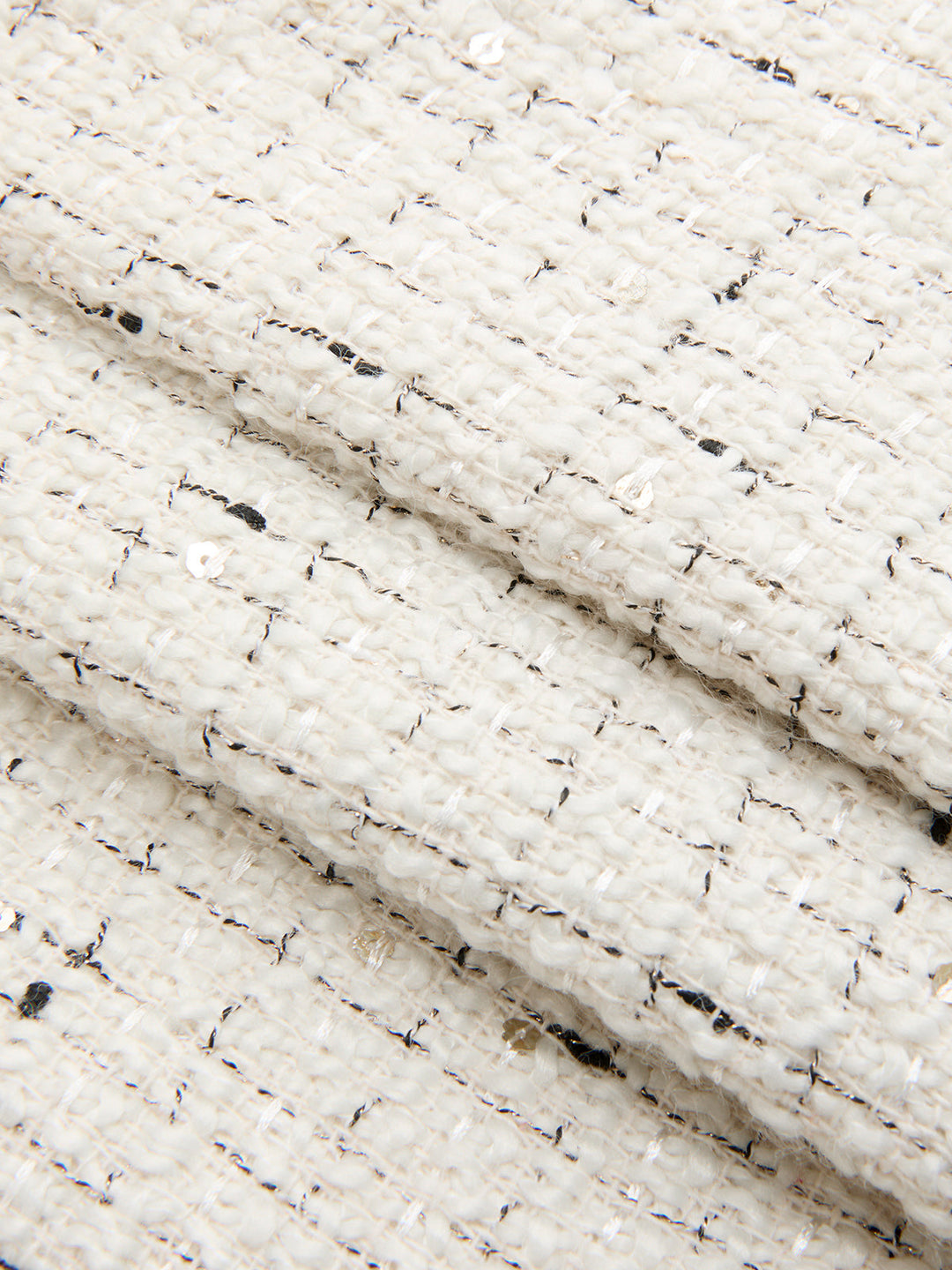 Close-up of ivory boucle tweed with metallic flecks and woven texture