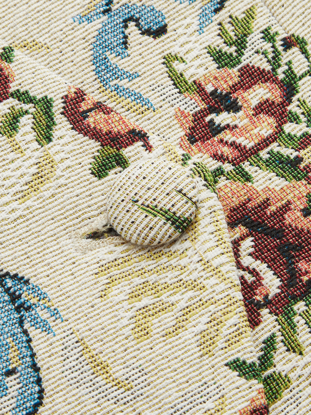 Macro of self-covered fabric button on cream floral tapestry waistcoat