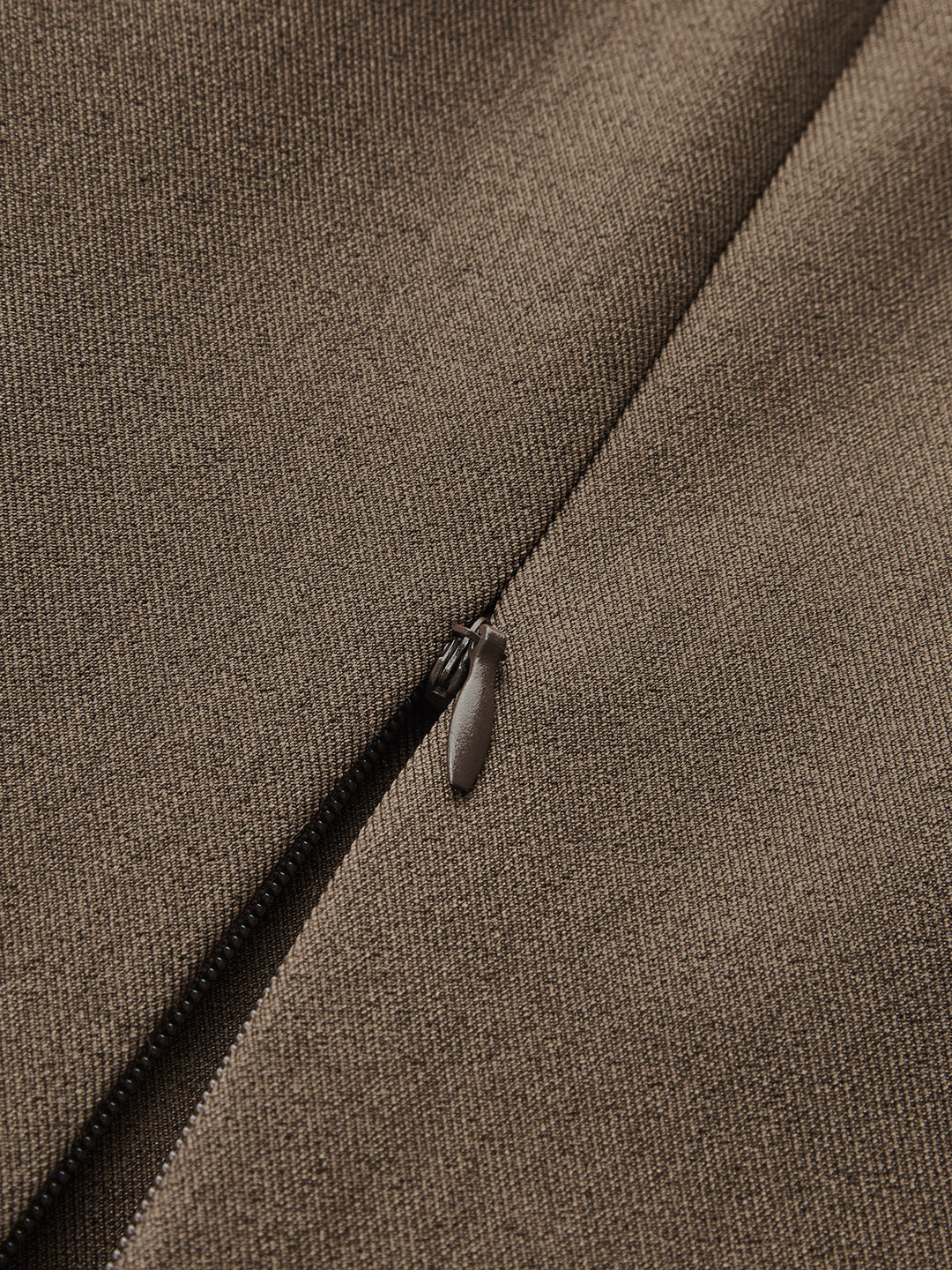Macro of the hidden side zip and fine brown woven fabric of the vest
