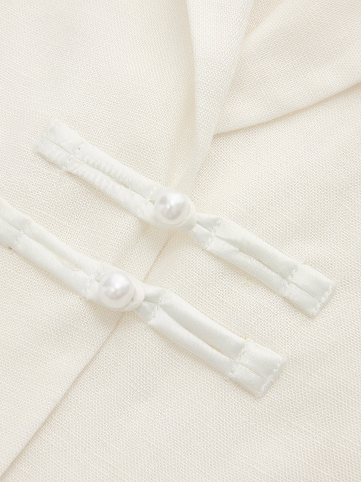 Close-up of the pearl frog button closures on the ivory linen blend blazer vest