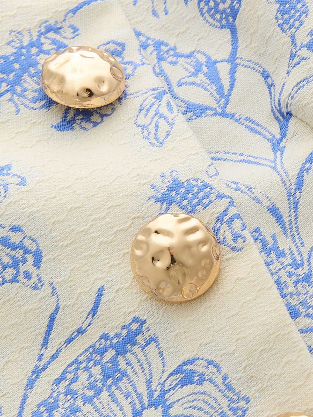 Close-up of hammered gold metal buttons on blue and cream floral jacquard
