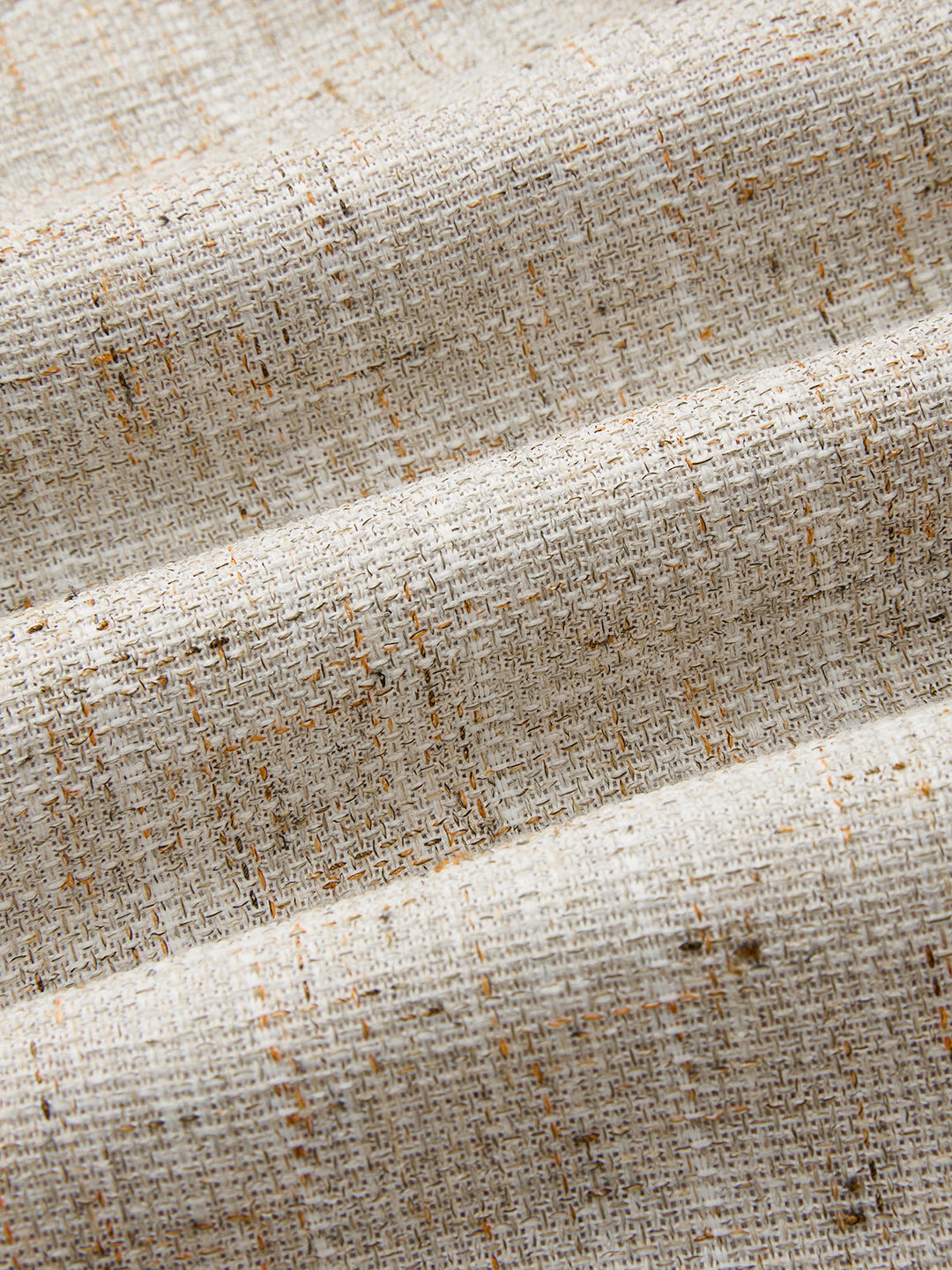Macro of natural beige woven tweed with caramel flecks from the asymmetric vest