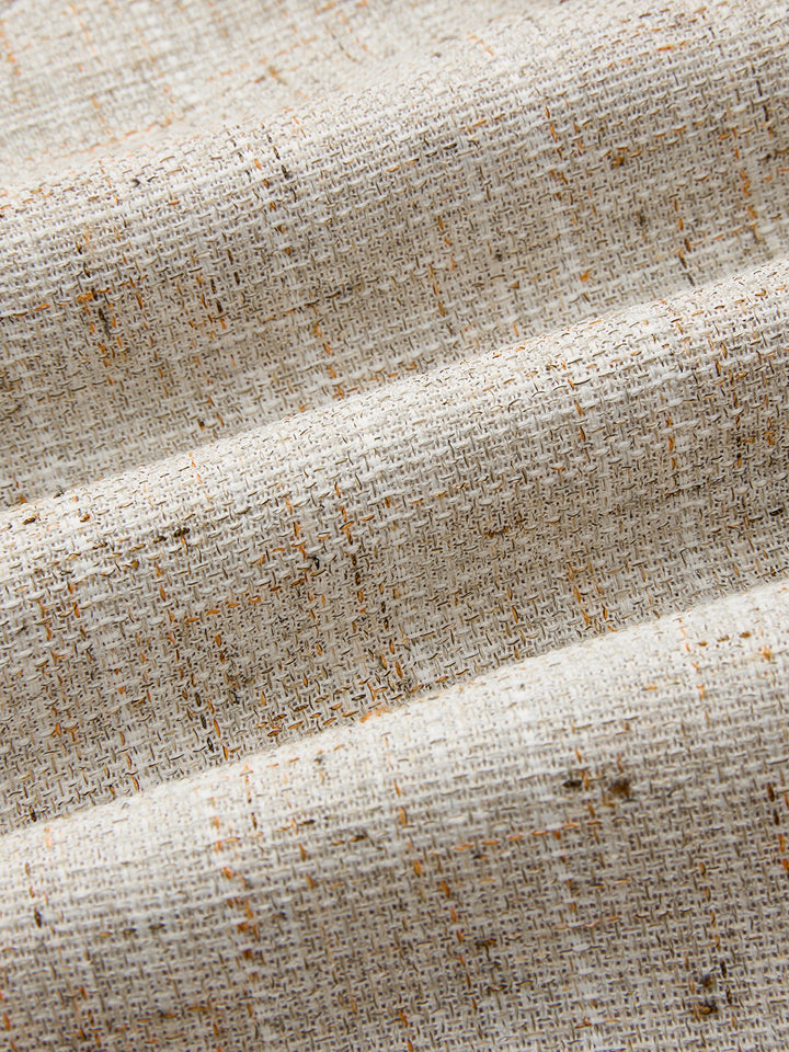 Macro of natural beige woven tweed with caramel flecks from the asymmetric vest