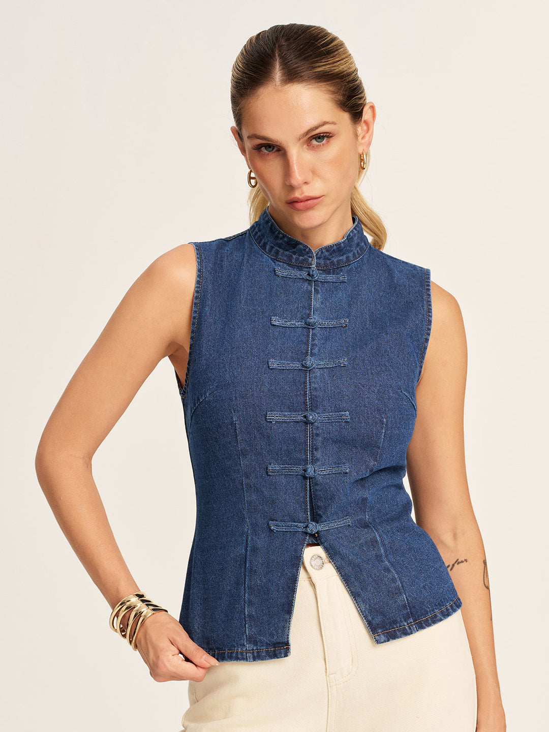 Model with hand on hip in the fitted denim frog button sleeveless vest