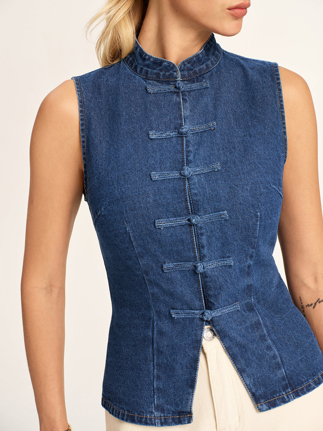 Close front view of the denim frog button vest showing stand collar and split hem