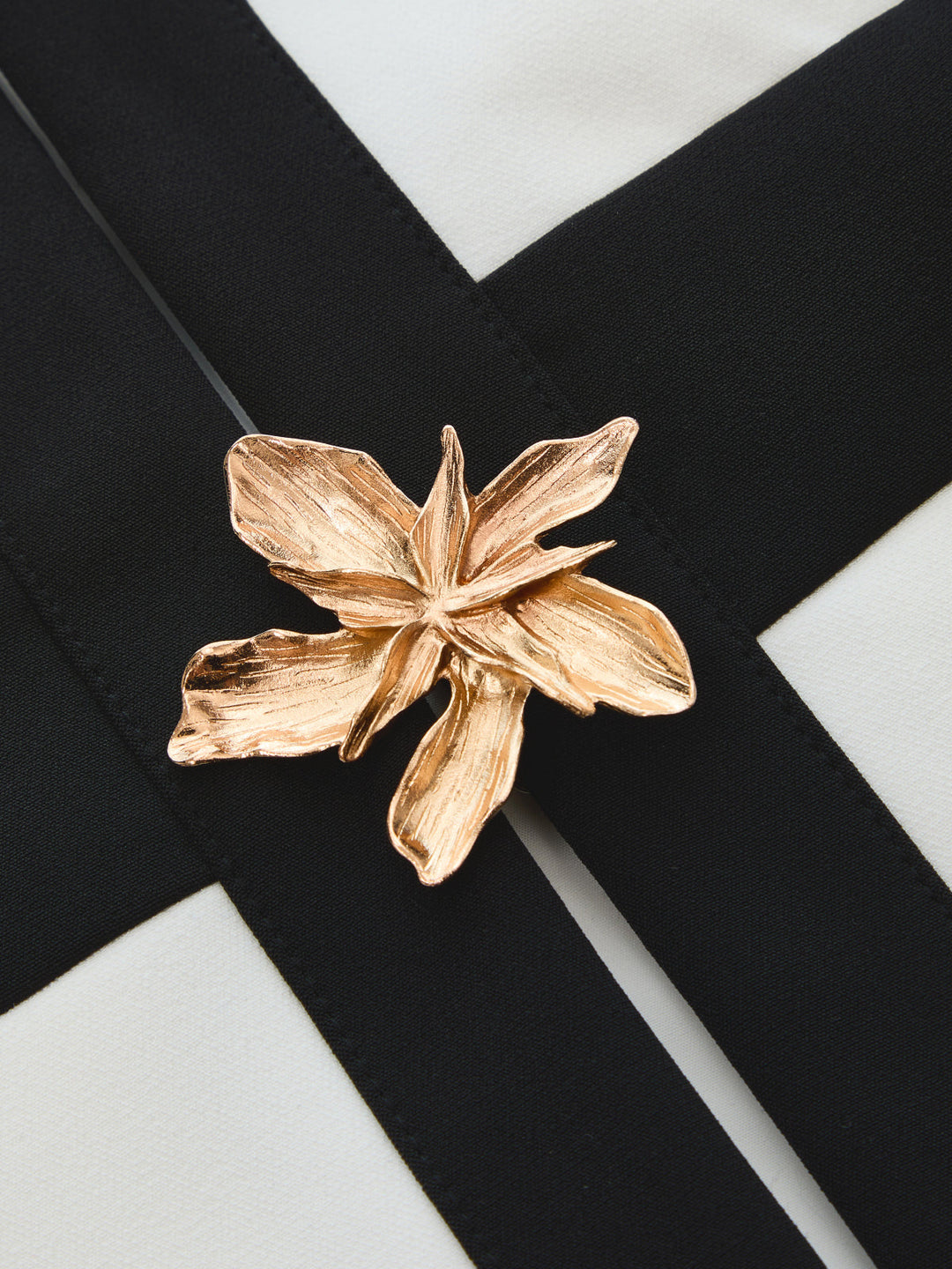 Close-up of the gold flower metal decor on the black and white colour block vest