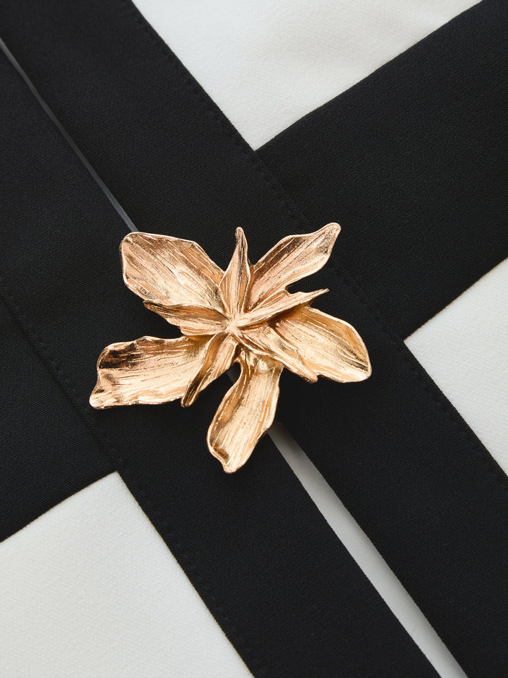 Close-up of the gold flower metal decor on the black and white colour block vest