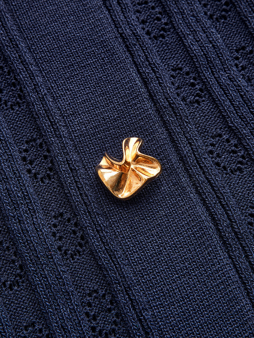 Close-up of a gold sculpted button on the navy denim collar knit dress